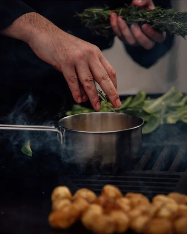 Préparation en cocotte avec des herbes fraîches sur le barbecue.