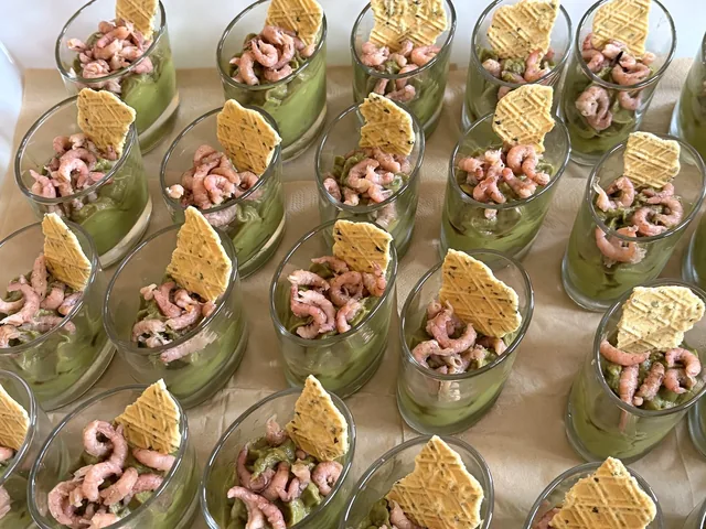 Plateau de verrines aux crevettes sur une base verte, accompagnées de tuiles croustillantes.